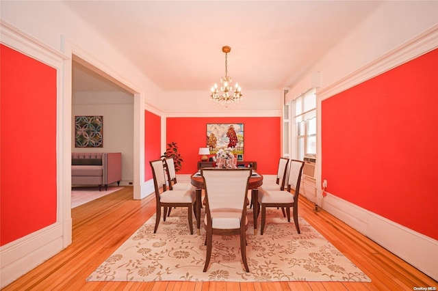 dining space featuring hardwood / wood-style floors, ornamental molding, and a chandelier