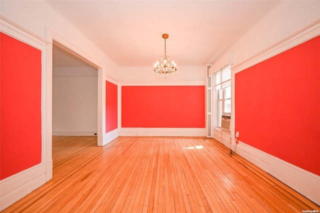 empty room with ornamental molding, a chandelier, and hardwood / wood-style flooring