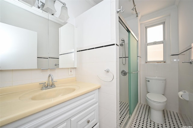 bathroom featuring toilet, vanity, a shower with shower door, tile walls, and ornamental molding