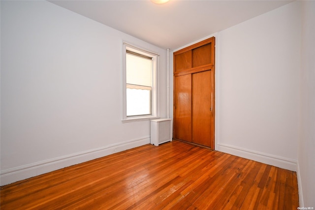 unfurnished room featuring radiator and hardwood / wood-style floors