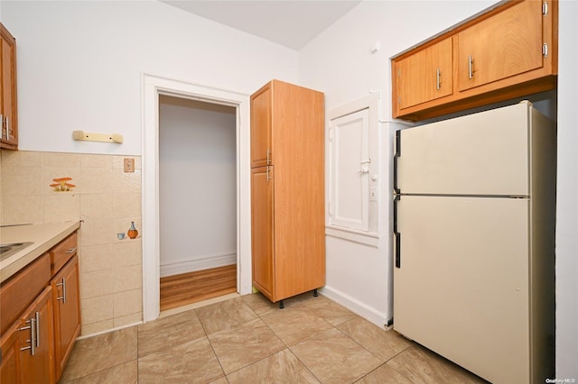 kitchen featuring white refrigerator and tile walls