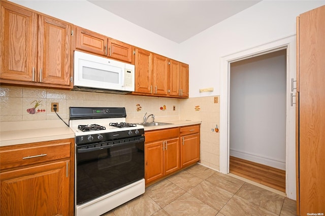 kitchen featuring decorative backsplash, white appliances, sink, and light hardwood / wood-style flooring