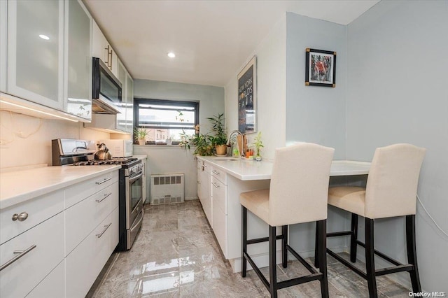 kitchen with stainless steel appliances, white cabinetry, a breakfast bar area, and sink