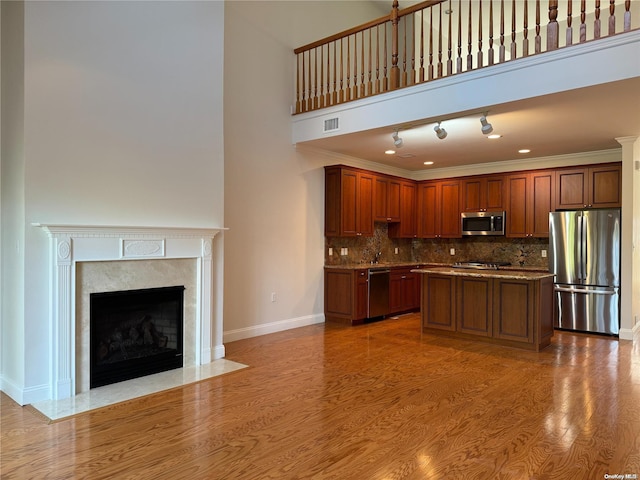 kitchen featuring a high ceiling, crown molding, a kitchen island, wood-type flooring, and stainless steel appliances