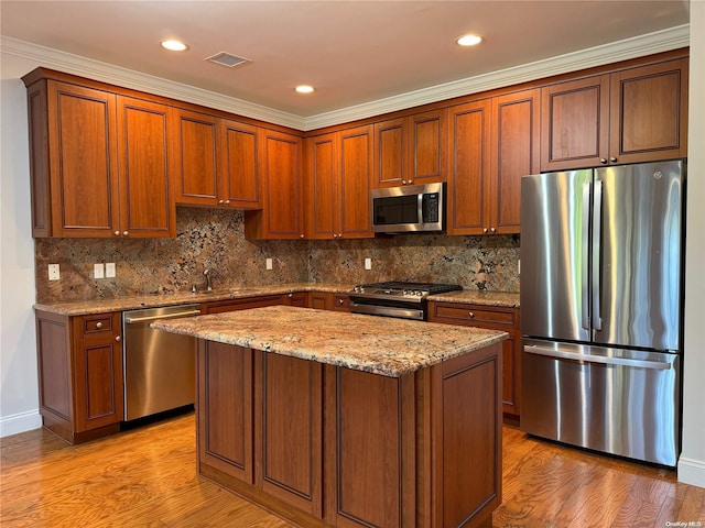 kitchen with appliances with stainless steel finishes, light wood-type flooring, tasteful backsplash, and ornamental molding