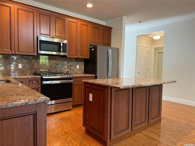 kitchen with decorative backsplash, stainless steel appliances, crown molding, a center island, and light hardwood / wood-style floors