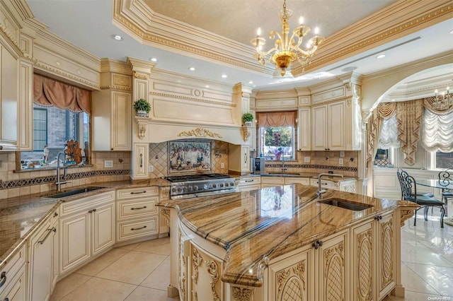 kitchen with stone counters, a kitchen island with sink, sink, and crown molding