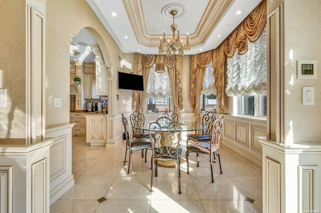 dining room featuring a raised ceiling, a healthy amount of sunlight, a notable chandelier, and ornamental molding