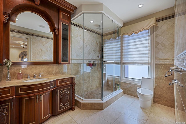 bathroom with walk in shower, tile patterned floors, toilet, vanity, and tile walls