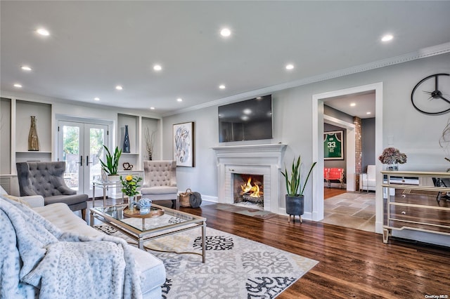 living room with french doors, light hardwood / wood-style floors, a brick fireplace, and crown molding