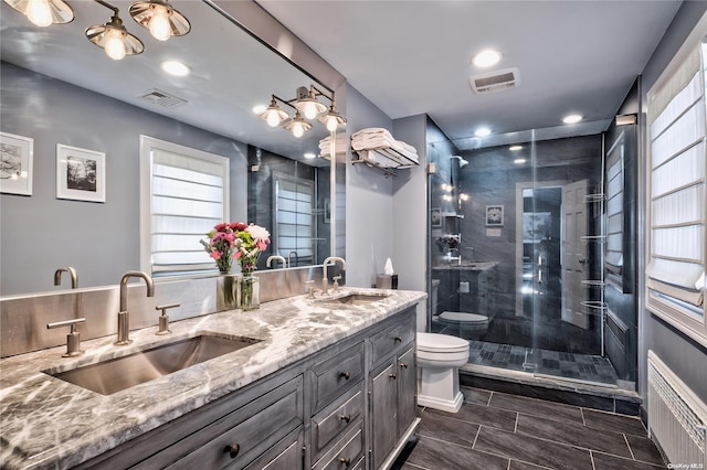 bathroom featuring radiator heating unit, vanity, toilet, and a shower with door