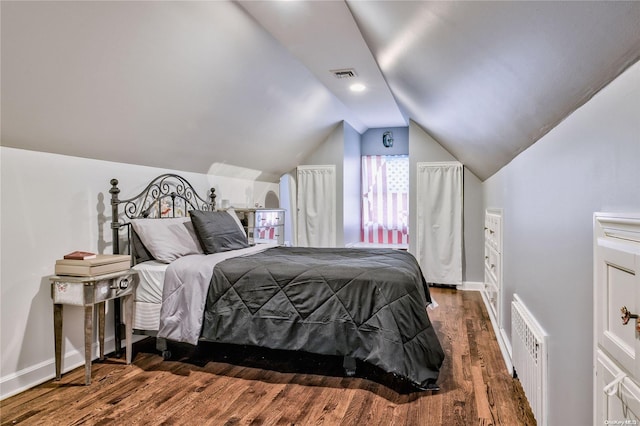 bedroom with vaulted ceiling, radiator, and dark wood-type flooring