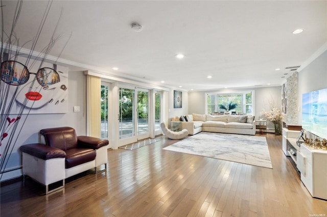 living room featuring light wood-type flooring, ornamental molding, and baseboard heating