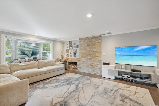 living room with a stone fireplace, ornamental molding, and hardwood / wood-style flooring