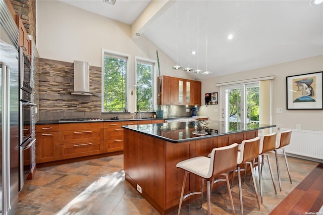 kitchen with pendant lighting, lofted ceiling with beams, wall chimney range hood, decorative backsplash, and a kitchen island