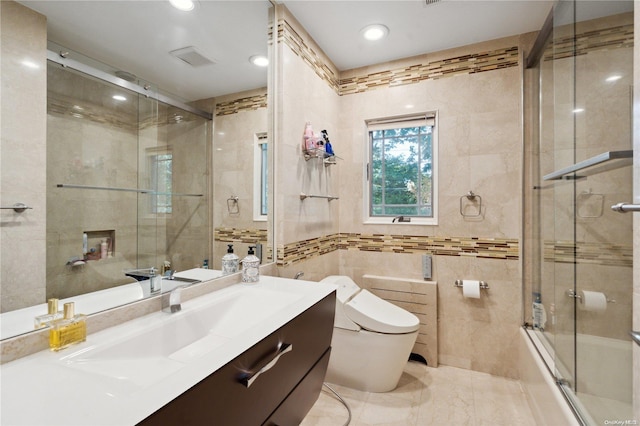 full bathroom with shower / bath combination with glass door, vanity, toilet, and tile walls