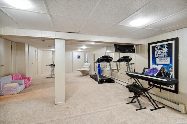 exercise room featuring carpet flooring, a drop ceiling, and wood walls