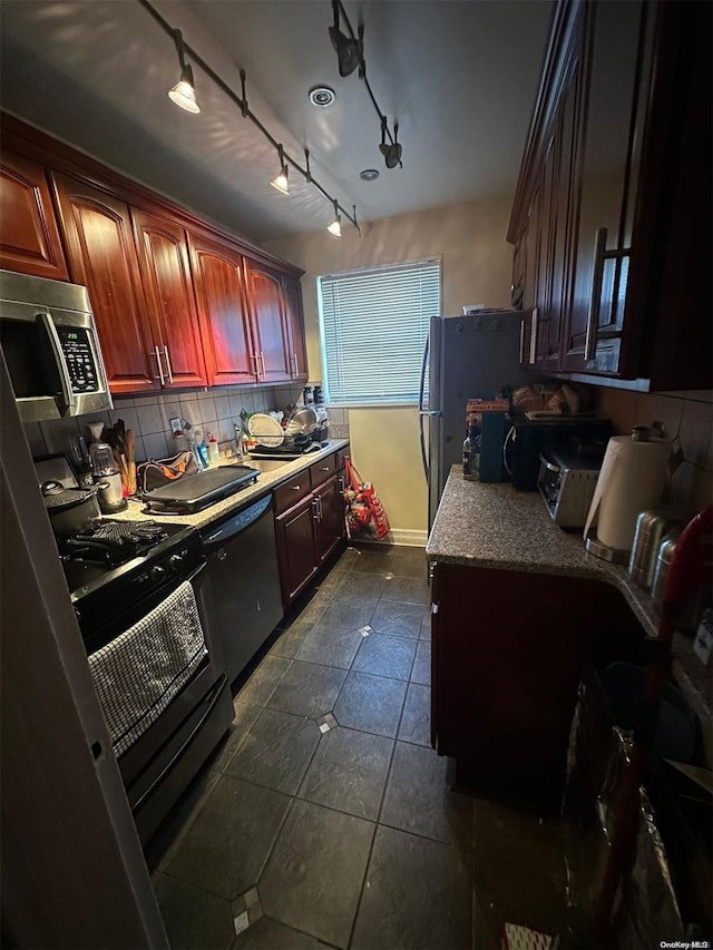 kitchen featuring track lighting, black appliances, sink, dark tile patterned floors, and tasteful backsplash