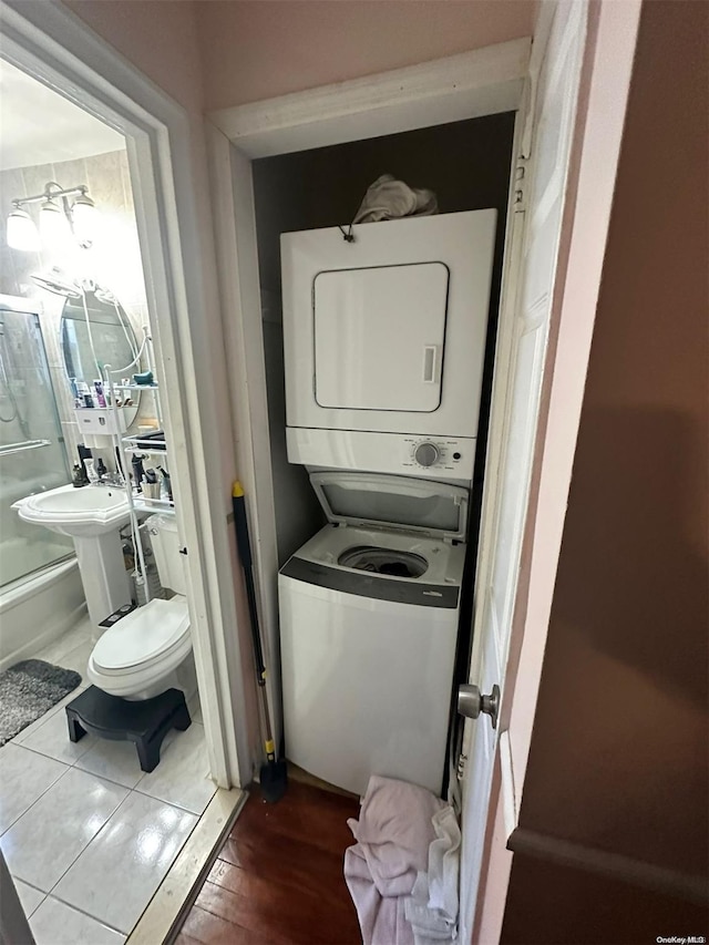 washroom with stacked washing maching and dryer and hardwood / wood-style flooring