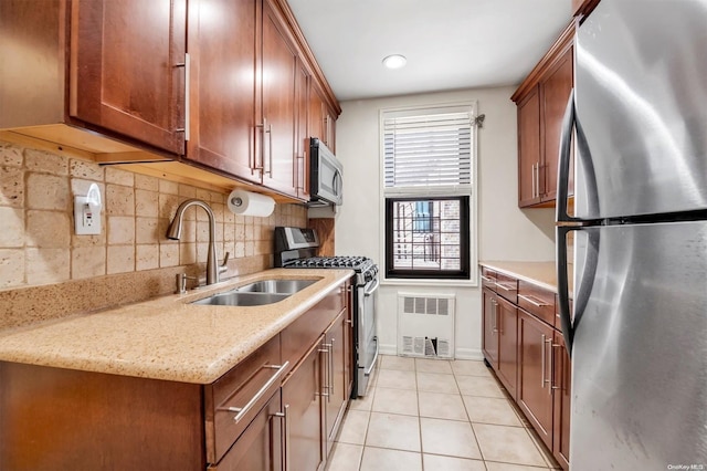 kitchen with light stone countertops, appliances with stainless steel finishes, backsplash, sink, and light tile patterned floors