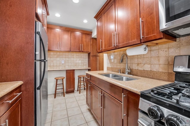 kitchen featuring light stone countertops, sink, tasteful backsplash, light tile patterned floors, and appliances with stainless steel finishes