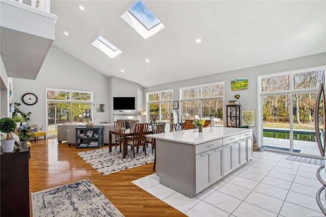 kitchen featuring gray cabinetry, high vaulted ceiling, light hardwood / wood-style floors, and a wealth of natural light