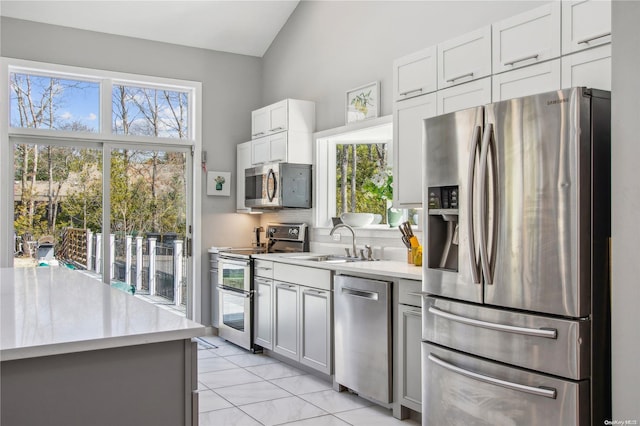 kitchen with appliances with stainless steel finishes, backsplash, sink, light tile patterned floors, and white cabinets