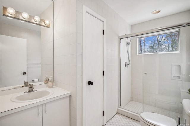 bathroom with tile patterned flooring, an enclosed shower, toilet, vanity, and tile walls