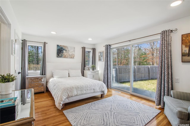 bedroom featuring access to exterior, multiple windows, and light wood-type flooring