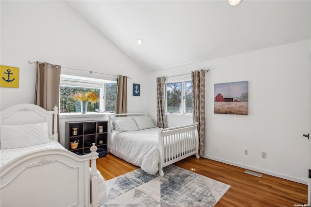 bedroom with hardwood / wood-style floors, high vaulted ceiling, and multiple windows