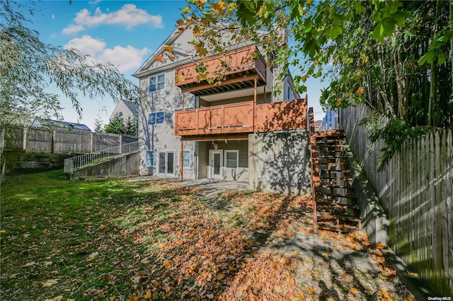 back of property featuring a balcony and a yard