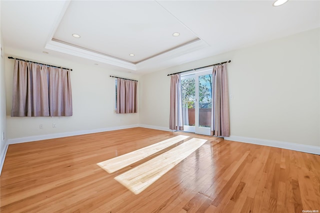 unfurnished room featuring wood-type flooring and a tray ceiling