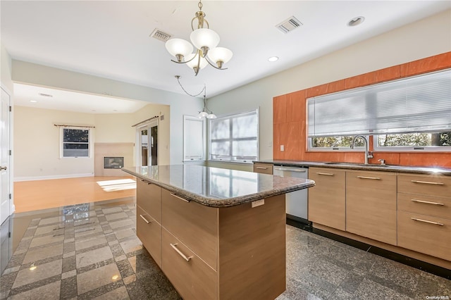 kitchen with stainless steel dishwasher, a healthy amount of sunlight, sink, and a chandelier