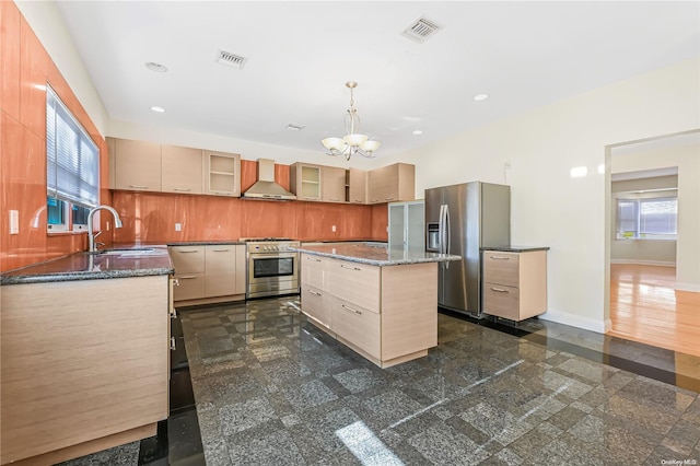 kitchen featuring pendant lighting, a center island, sink, wall chimney exhaust hood, and appliances with stainless steel finishes