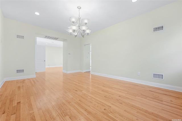 empty room featuring a chandelier and light wood-type flooring