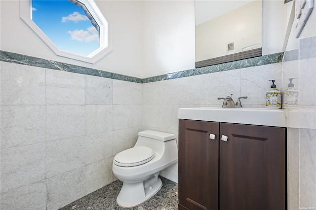 bathroom with vanity, toilet, and tile walls