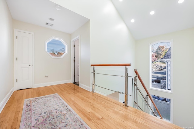 entrance foyer with wood-type flooring, vaulted ceiling, and a healthy amount of sunlight