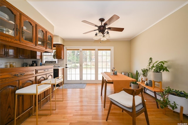 dining area featuring light wood-type flooring, ceiling fan, and ornamental molding