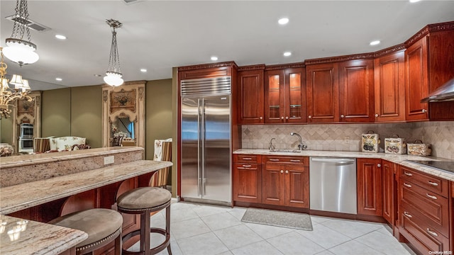 kitchen with hanging light fixtures, a breakfast bar area, decorative backsplash, light tile patterned floors, and appliances with stainless steel finishes