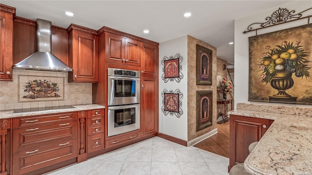 kitchen featuring black electric stovetop, light hardwood / wood-style flooring, wall chimney exhaust hood, light stone countertops, and double oven