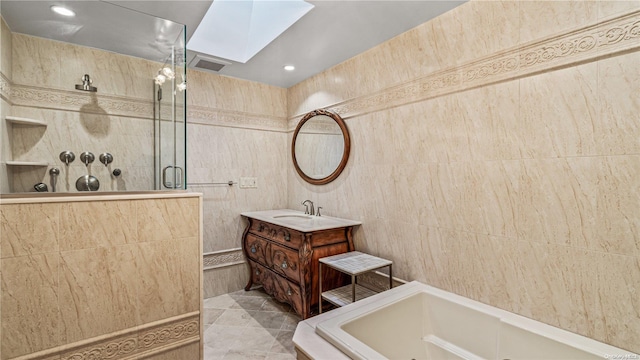 bathroom with a skylight, plus walk in shower, and tile walls