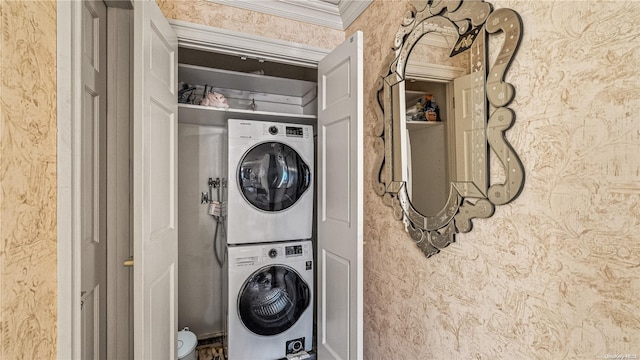 clothes washing area featuring stacked washer / dryer and crown molding