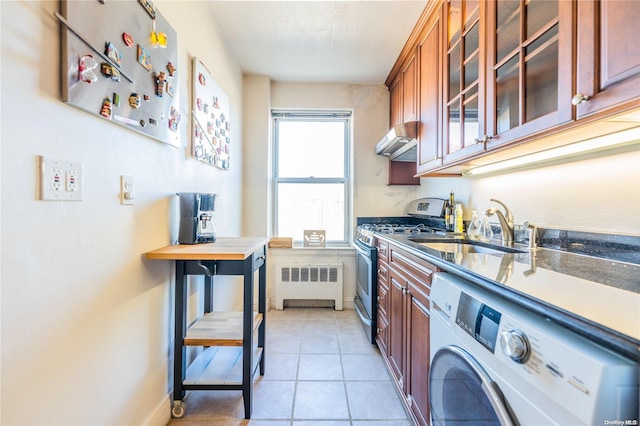 kitchen with radiator, sink, stainless steel gas stove, light tile patterned flooring, and washer / dryer