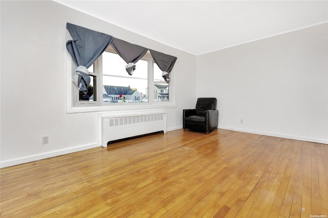 unfurnished living room with light hardwood / wood-style flooring, radiator, and crown molding