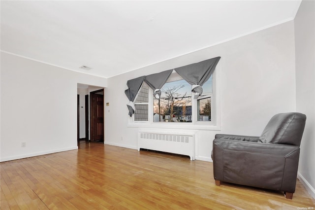 living area featuring light hardwood / wood-style floors, radiator heating unit, and ornamental molding