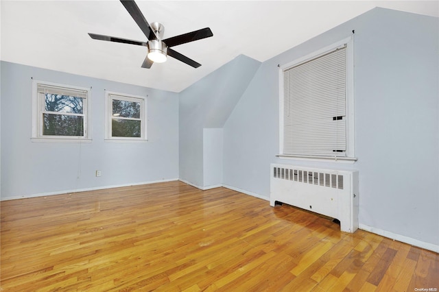 bonus room featuring radiator heating unit, light wood-type flooring, ceiling fan, and lofted ceiling