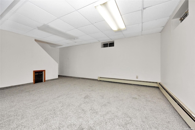 basement with carpet, a paneled ceiling, and a baseboard heating unit