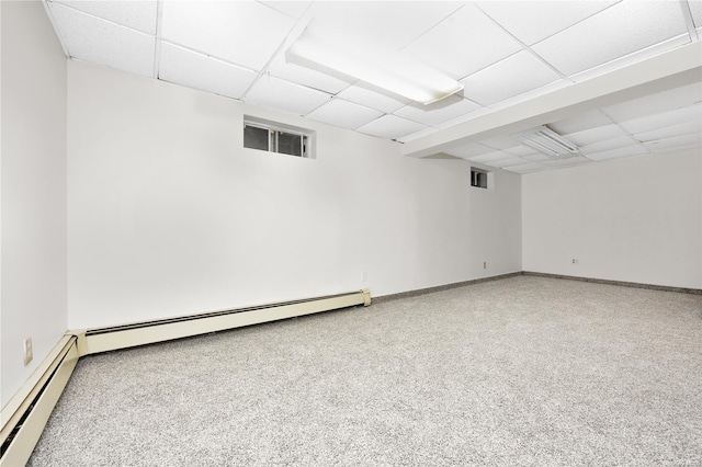 basement featuring carpet flooring, a drop ceiling, and a baseboard heating unit