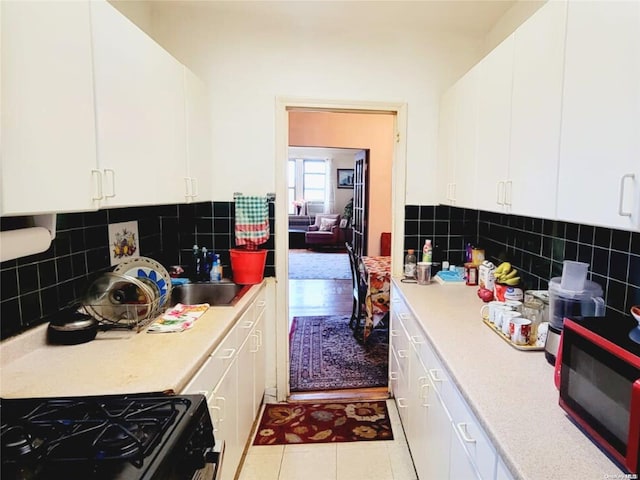 kitchen featuring backsplash, white cabinets, black appliances, and light tile patterned floors