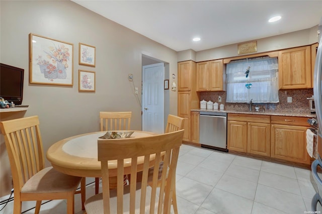 kitchen featuring dishwasher, backsplash, sink, light tile patterned floors, and light stone counters